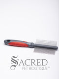 A double sided dog grooming comb with a red and grey handle. The comb has narrow teeth on one side and wider teeth on the other. On a white background with a grey Sacred Pet Boutique watermark.