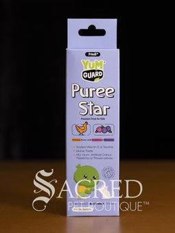 Four Yumguard Puree Star pet treats in different flavours (Fish and Mango, Chicken and Papaya, Fish and Apple, Chicken and berries) in colourful packaging, displayed on a wooden surface against a black background. With a white Sacred Pet Boutique watermark.