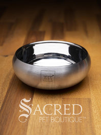 A beautifully styled curved sided double walled steel bowl with brand name ZEEZ etched on the outer brushed finished edge shows the highly polished inner where the brand name is embossed on the base. Place on a wooden table and watermarked with Sacred Pet Boutique