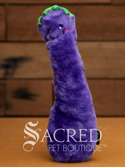 A red furry chilli pepper cat toy with a happy smiling face and a green top or hat sits on a wooden surface.