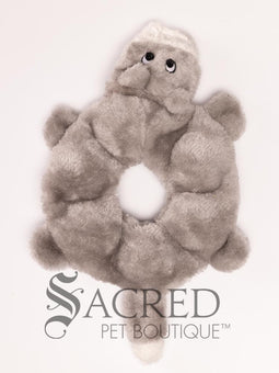 A plush dog toy resembling a wolf in a neutral grey colour, placed on a flat surface, with the brand 'Sacred Pet Boutique' visible.