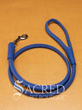 A blue soft round leather dog leash with a metal clasp. Leashes are 122cm long and the leather has a diameter of 1cm. Image displayed on a golden background with 'SACRED PET BOUTIQUE' watermark.