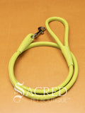 A green soft round leather dog leash with a metal clasp. Leashes are 122cm long and the leather has a diameter of 1cm. Image displayed on a golden background with 'SACRED PET BOUTIQUE' watermark.