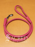 A pink soft round leather dog leash with a metal clasp. Leashes are 122cm long and the leather has a diameter of 1cm. Image displayed on a golden background with 'SACRED PET BOUTIQUE' watermark.