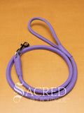 A purple soft round leather dog leash with a metal clasp. Leashes are 122cm long and the leather has a diameter of 1cm. Image displayed on a golden background with 'SACRED PET BOUTIQUE' watermark.