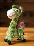 A cute crocheted green donkey with an impish grin stands on a wooden table with a wooden wall behind. Suitable for small, toy and teacup dogs, the crochet toys squeak and will floss teeth as they play.