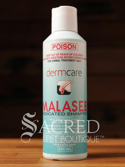 A bottle of Dermcare Malaseb medicated shampoo for pets, with a label indicating it is an antifungal shampoo for dogs and cats, and that it is not intended for treating animals other than chickens. A250ml bottle shown on a wooden surface and features Sacred Pet Boutique watermark.