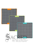 Three LickiMat Tuff Buddy mats in three different colours - orange, green and blue. They're on a white background and has a grey Sacred Pet Boutique watermark. 