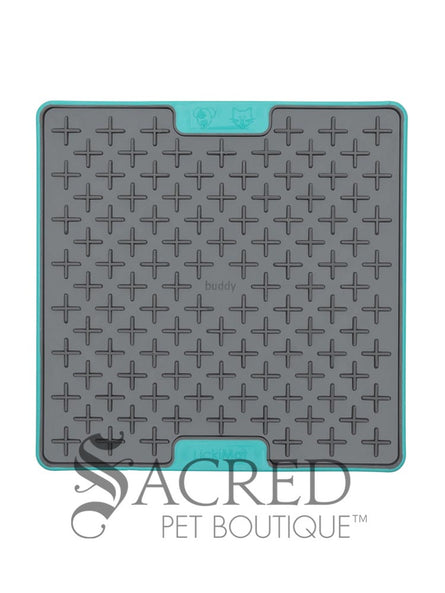 The LickiMat Tuff Buddy is an interactive slow-feeding mat designed for dogs and cats. Unlike the flexible rubber models the Tuff variation featuress a rigid, tough polypropylene backing with non-slip rubber feet. This image shows a grey cross-maze texturing paired with a durable turquoise base. Buddy, with its cross maze design is perfect for thick, sticky treats like peanut butter, wet food or soggy biscuits. There is a white background and a grey Sacred Pet Boutique watermark. 