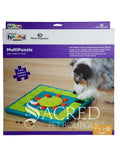 The packaging for the MultiPuzzle treat puzzle dog toy. The top section shows the Outward Hound and Nina Ottosson logos. The toy name Multipuzzle appears under this and ha the tagline Spin, Slide & Treat. The packaging also details the key features of the toy. There is a white Sacred Pet Boutique watermark. 