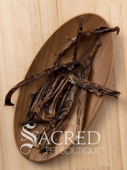 A wooden plate containing dried pork chews for dogs. On a wooden background, with a white Sacred Pet Boutique watermark.