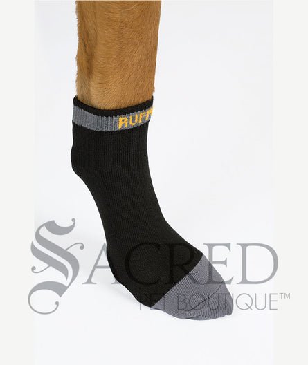 A single Granite Grey Bark'n'Boot liner is shown on a dogs foot. You can see what it looks like on the dogs paw. The main colour is black, with mid grey toe, plus a grey band across the opening of the sock with the Ruffwear name in yellow.