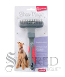 From Yours Droolly, the Shear Magic medium Coat Rake is in it's packaging showing an Airedale Terrier. The rake has a single row of spinning teeth and a red and grey handle. A Sacred Pet Boutique watermark in grey print.